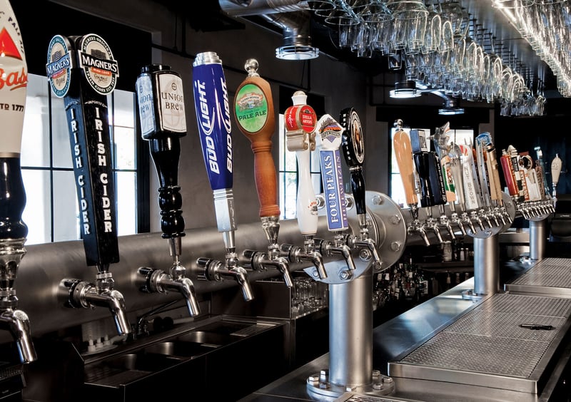 Line up of Perlick draft beer dispensers with each handle labeled with brand's logos.